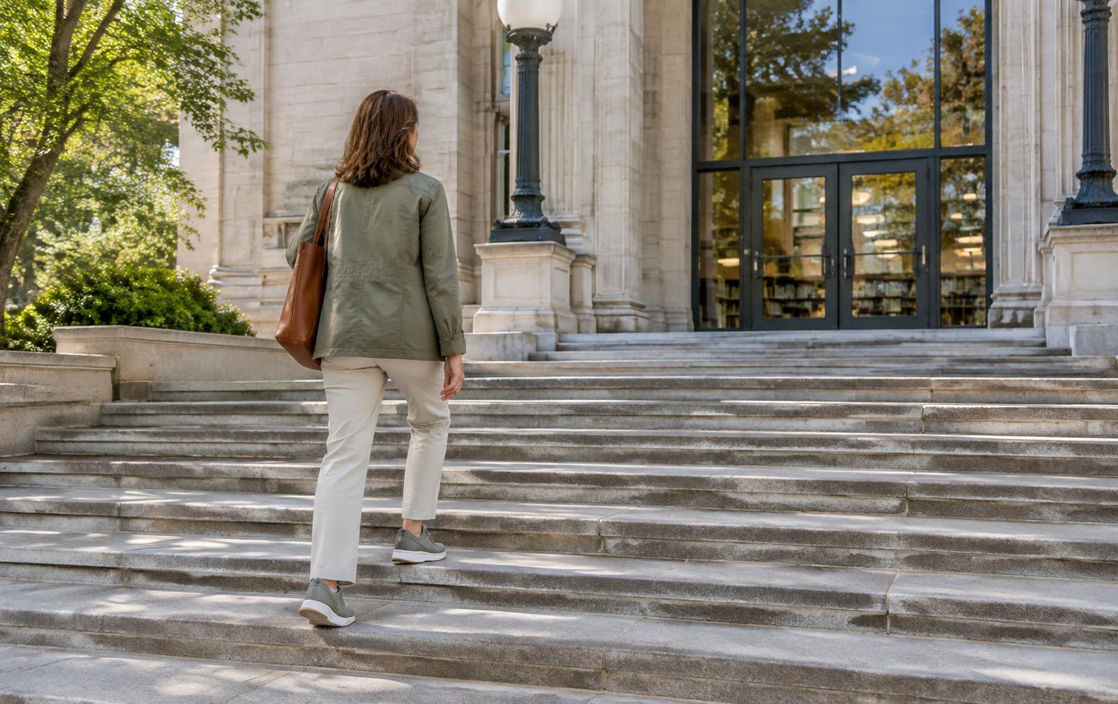 A woman sitting on library steps in warm light, looking ahead with quiet confidence